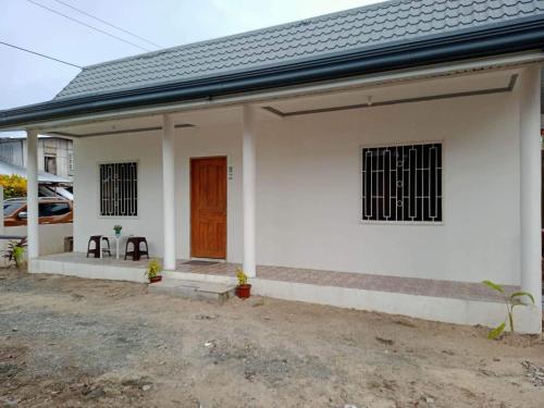 een klein wit huis met een bruine deur bij Meghan’s Homestay in General Luna