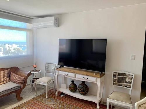 sala de estar con TV de pantalla plana en la pared en Divino departamento a estrenar en la península., en Punta del Este