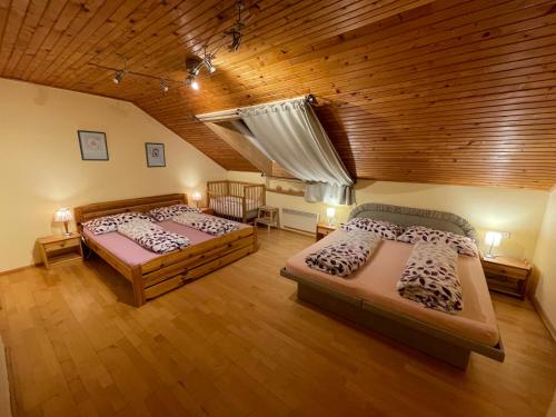 two beds in a room with a wooden ceiling at Ubytování Duškovi in Lipno nad Vltavou