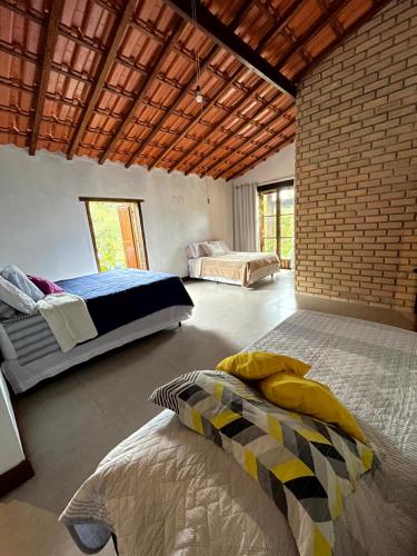 - une chambre avec 2 lits et un mur en briques dans l'établissement Casa Mirante do Capão, à Palmeiras