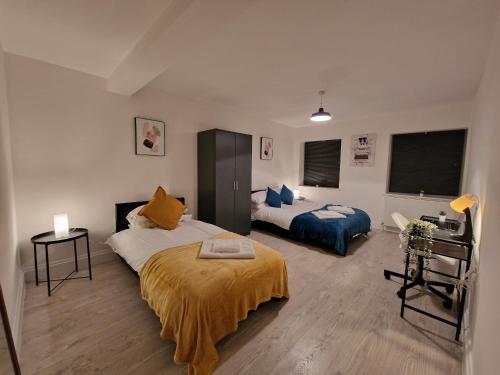 a bedroom with two beds and a desk in it at Cosy 2 Bedroom Apartment by ReeAni Stays with Wifi, Netflix & Private Parking in Uxbridge