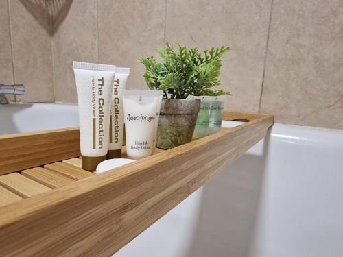 a bathroom shelf with two products on a bath tub at Cosy 2 Bedroom Apartment by ReeAni Stays with Wifi, Netflix & Private Parking in Uxbridge