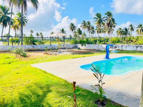 a swimming pool in a yard with palm trees at Pousada Iandê Patacho in Pôrto de Pedras