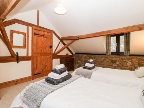 two beds in a room with wooden ceilings at Bullfinch Cottage in Leominster