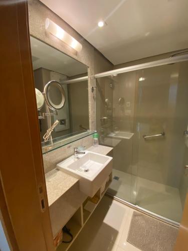 a bathroom with a sink and a shower and a mirror at Flat Jade Hotel Brasília in Brasília