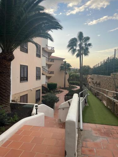 a building with palm trees next to a walkway at Sweet home ocean golf resort in San Miguel de Abona
