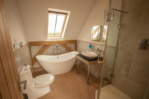 a bathroom with a tub and a toilet and a sink at The Old Barn, Newclose Farm in Yarmouth