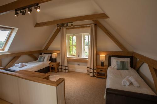 a attic room with two beds and a window at The Old Barn, Newclose Farm in Yarmouth