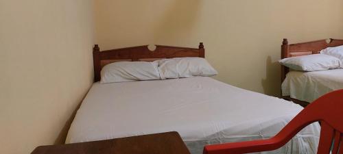 a small bedroom with a white bed and a red chair at Posada Tzeltal in El Otatal