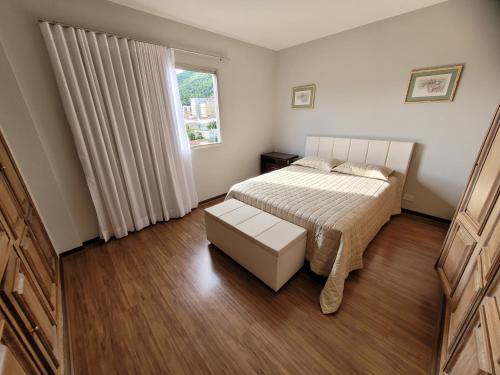 um pequeno quarto com uma cama e uma janela em Apartamento Vista Palace Centro em Poços de Caldas