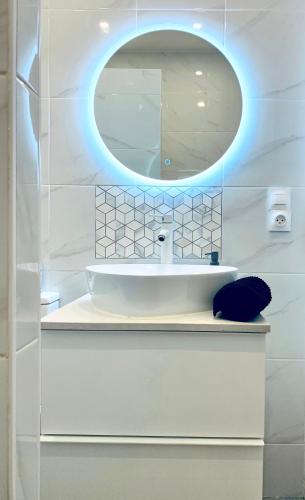 une salle de bain blanche avec un lavabo et un miroir dans l'établissement New flat near Paris-Stade de France, à Aubervilliers