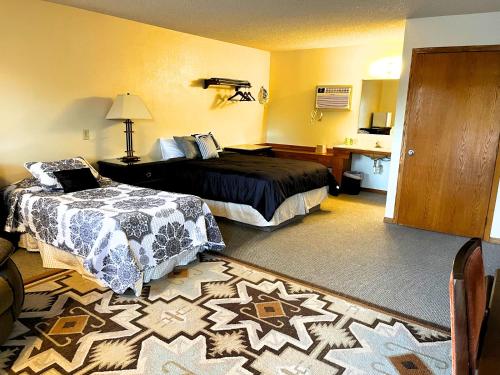 a hotel room with two beds and a rug at Furnas County Lodging in Beaver City
