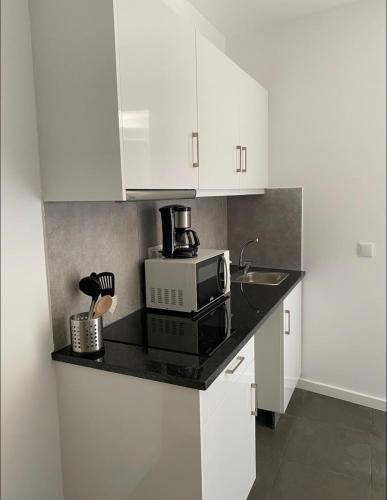 a kitchen with a microwave and a sink and white cabinets at DDM Studio - O paraíso do Sítio da Nazaré in Nazaré