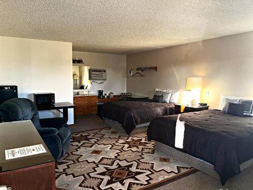 a hotel room with two beds and a chair at Furnas County Lodging in Beaver City