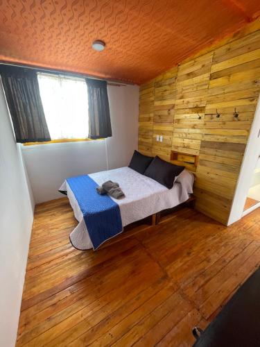 a bedroom with a bed and a wooden wall at Glamping en villa in Villa de Leyva