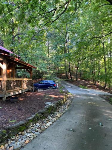 a house with a car parked next to a road at 1850’s Settlers Cabin at Wethero Ridge & Theater in Hendersonville
