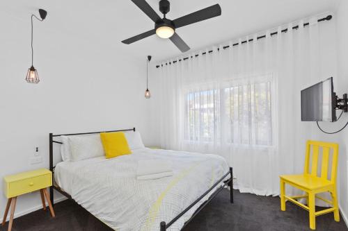 a bedroom with a bed with a ceiling fan and a yellow chair at Casino Views in Apollo Bay