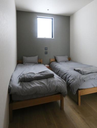 two twin beds in a room with a window at Niseko Bisha 美舎 Villas in Niseko