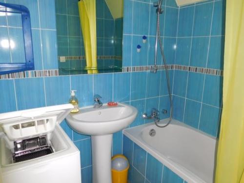 une salle de bain carrelée bleue avec un lavabo et une baignoire dans l'établissement Maison typique vendéenne, piscine privée, proche plage, 4 pers, La Faute-sur-Mer - FR-1-476-162, à La Faute-sur-Mer