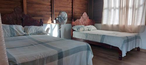 two beds in a bedroom with wooden walls and windows at Posada Tzeltal in El Otatal