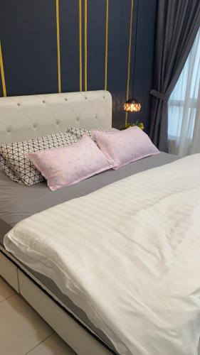a white bed with two pink pillows on it at Ana Homestay in Batu Pahat