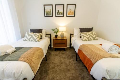 a room with two beds and a table with a lamp at A touch of Luxury in Chch CBD in Christchurch