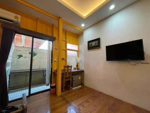sala de estar con TV de pantalla plana en la pared en tamarind guesthouse, en Phra Nakhon Si Ayutthaya