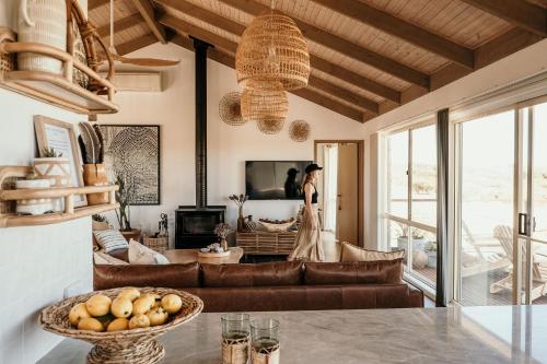 a woman is standing in a living room at Sunsets on Martyrs Coastal Luxury Beach House Peterborough in Peterborough