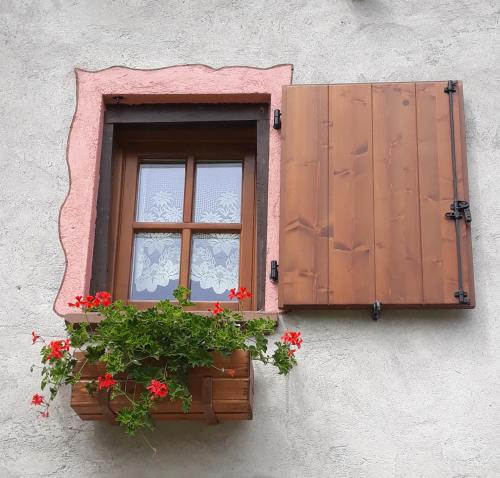 a window with red flowers in a window box at Casa All'Alpe in Anzino
