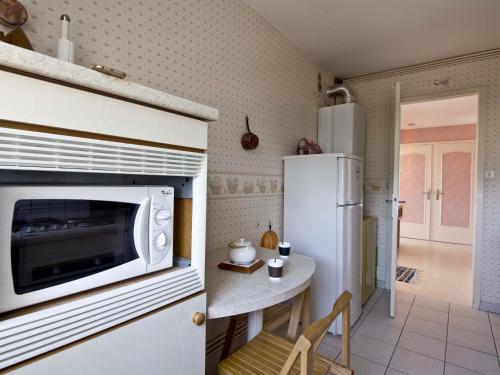 La cuisine est équipée d'un four micro-ondes, d'une table et d'un réfrigérateur. dans l'établissement Appartement T2 proche plage avec loggia et un animal admis - FR-1-92-649, à La Pironnière