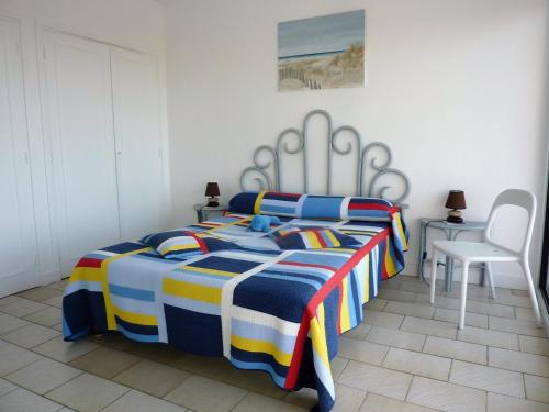 - une chambre avec un lit et une couverture rayée colorée dans l'établissement T2 rénové avec balcon, parking couvert, animaux admis - FR-1-92-583, à Les Sables-dʼOlonne