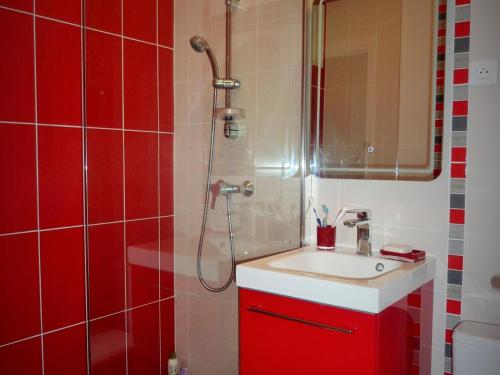 La salle de bains rouge est pourvue d'un lavabo et d'une douche. dans l'établissement T2 rénové avec balcon, parking couvert, animaux admis - FR-1-92-583, à Les Sables-dʼOlonne
