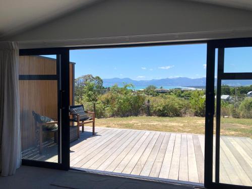 a view of a deck with a bench through a window at Ruby Bay Loft Apartment in Nelson