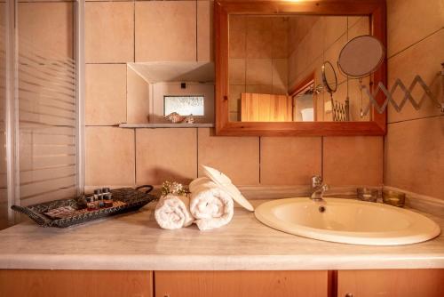 y baño con lavabo, espejo y toallas. en Traditional cottage near Kissamos and Falassarna 2 feel like home properties, en Áyios Vasílios