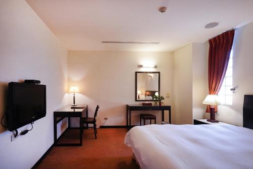 台中市にあるHerkang Hotelのベッドとテレビが備わるホテルルームです。
