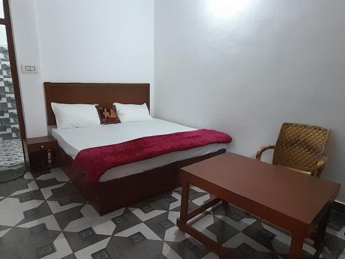 a small bedroom with a bed and a table at Rani Homestay Khajuraho in Khajurāho