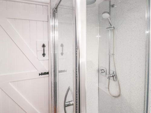 a shower with a glass door in a bathroom at Clementine Cottage in Tenby