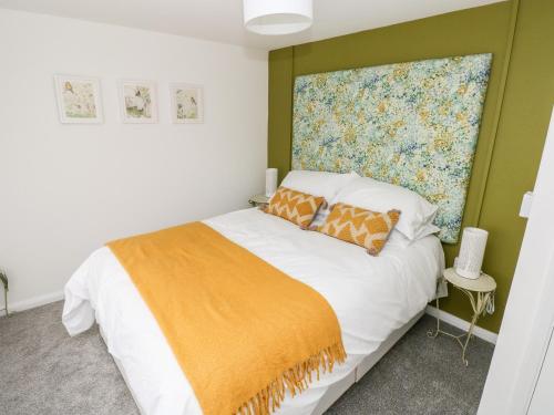 a bedroom with a bed with an orange blanket at Rosemary Cottage in Tenby