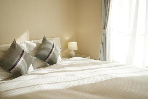 a large white bed with pillows and a window at Choetsu in Kyoto