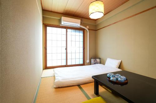 a room with a bed and a table and a window at Choetsu in Kyoto