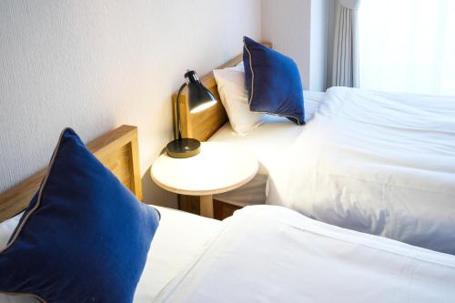 two beds with blue pillows in a room at Choetsu in Kyoto