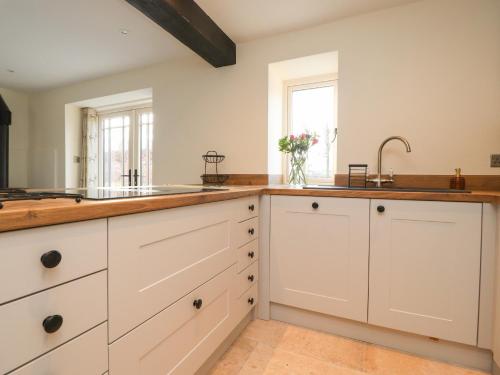 uma cozinha com armários brancos e um lavatório em The Byre em Preston