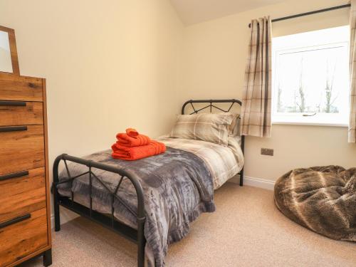 um quarto com uma cama com uma toalha laranja em The Byre em Preston