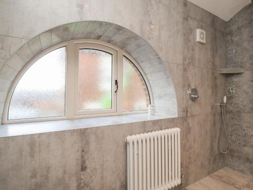 a bathroom with an arched window and a shower at Thy Owd Sty in Preston