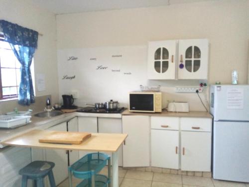 a kitchen with white cabinets and a table and a refrigerator at Sea Valley Villa in Port Alfred