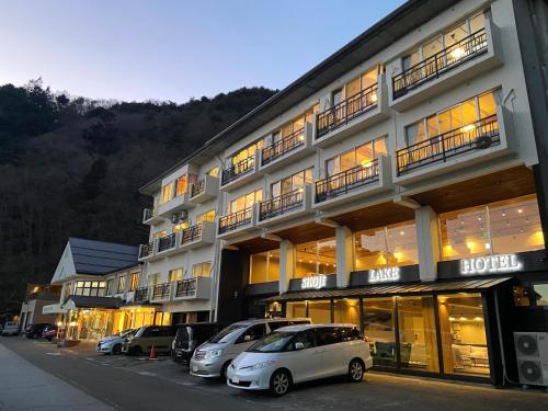 a large building with cars parked in front of it at Shoji Lake Hotel in Fujikawaguchiko