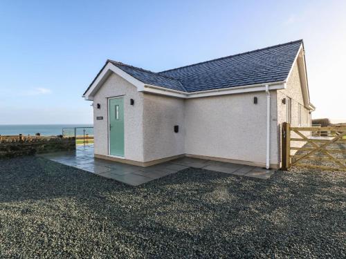 a small house with a green door on a beach at Y Gorlan in Moelfre
