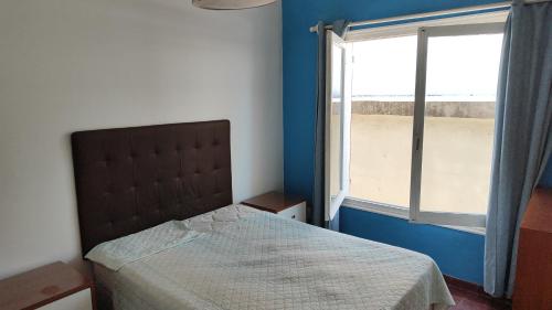 Un dormitorio con una cama y una ventana grande. en Apartamento sobre Gorlero, en Punta del Este