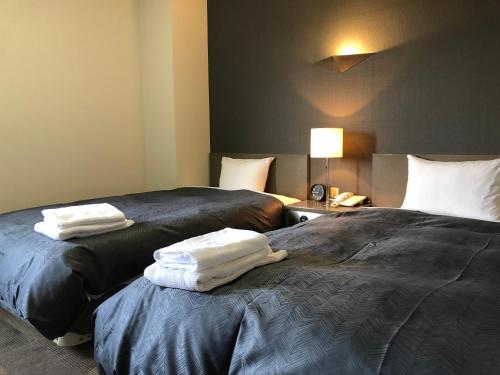two beds in a hotel room with towels on them at Hotel New White House in Rumoi
