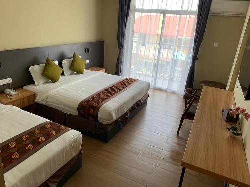 um quarto de hotel com duas camas e uma mesa em Wing Tat Grand Hotel em Semporna